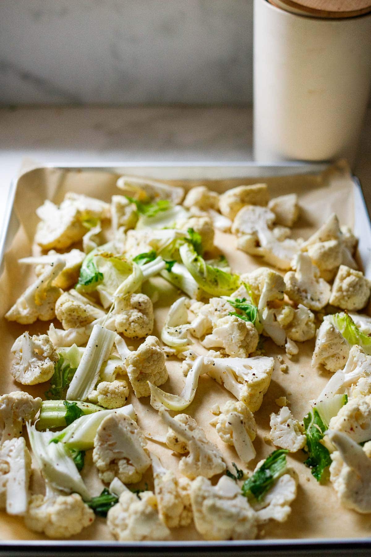 spreading out the cauliflower on a sheet pan. 