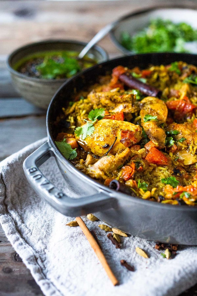 An authentic & insanely delicious recipe for Chicken Biryani with Cilantro Yogurt Sauce. A Vegetarian option included as well as detailed step by step instructions. | www.feastingathome.com #chickenbiryani #indianrice #indianchicken