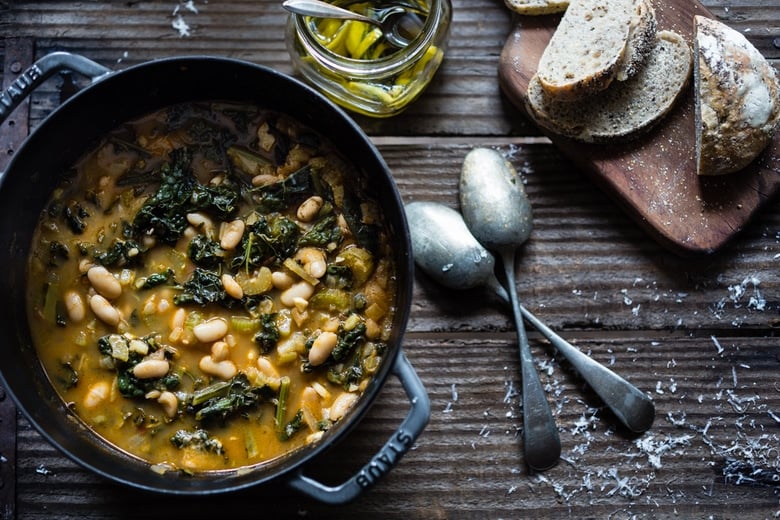 A flavorful hearty stew from Tuscany, called Ribollita with Cannellini beans, lacinato kale, and vegetables, served with crusty bread, drizzled with a Lemon Rosemary Garlic Oil. | www.feastingathome.com