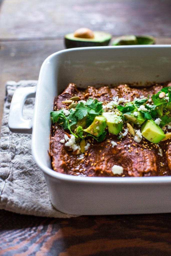 These vegetarian Butternut Enchiladas are filled with roasted butternut squash and black beans and baked in a simple, yet flavorful Mole Sauce. Topped with cilantro, avocado and toasted sesame seeds and pumpkin seeds, serve this up with this Mexican slaw for a fast and delicious vegetarian dinner, perfect for fall!  Vegan adaptable! 