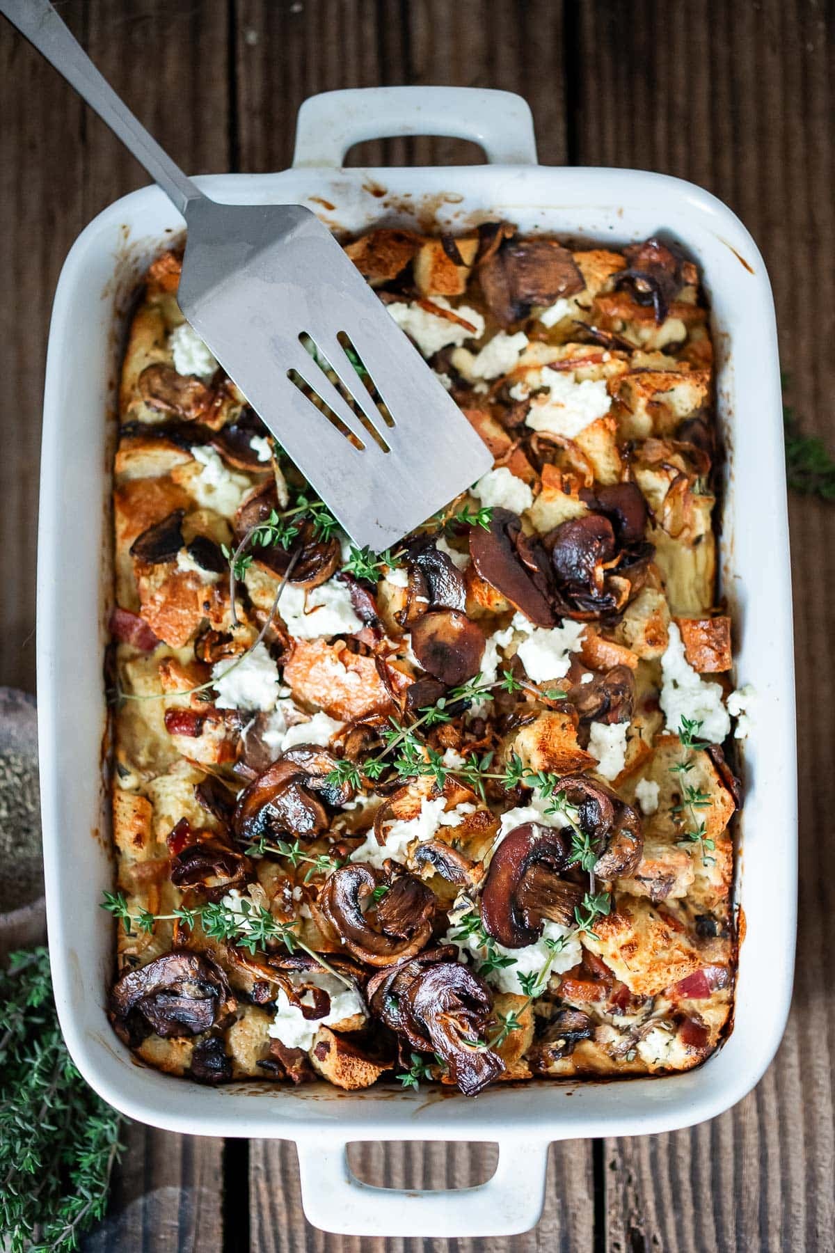 breakfast strata with mushrooms, goat cheese, and thyme in a casserole dish for Mother's day brunch. 
