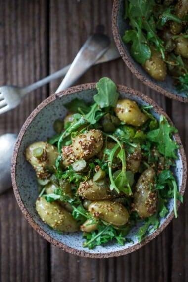 A healthy lightened up Potato Salad with Mustard Seed dressing, cornichons and baby Arugula. | www.feastingathome.com