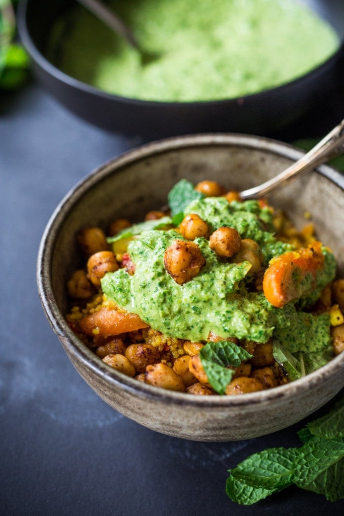 Tunisian couscous bowl with chickpeas, carrots, and mint topped with green harissa sauce.