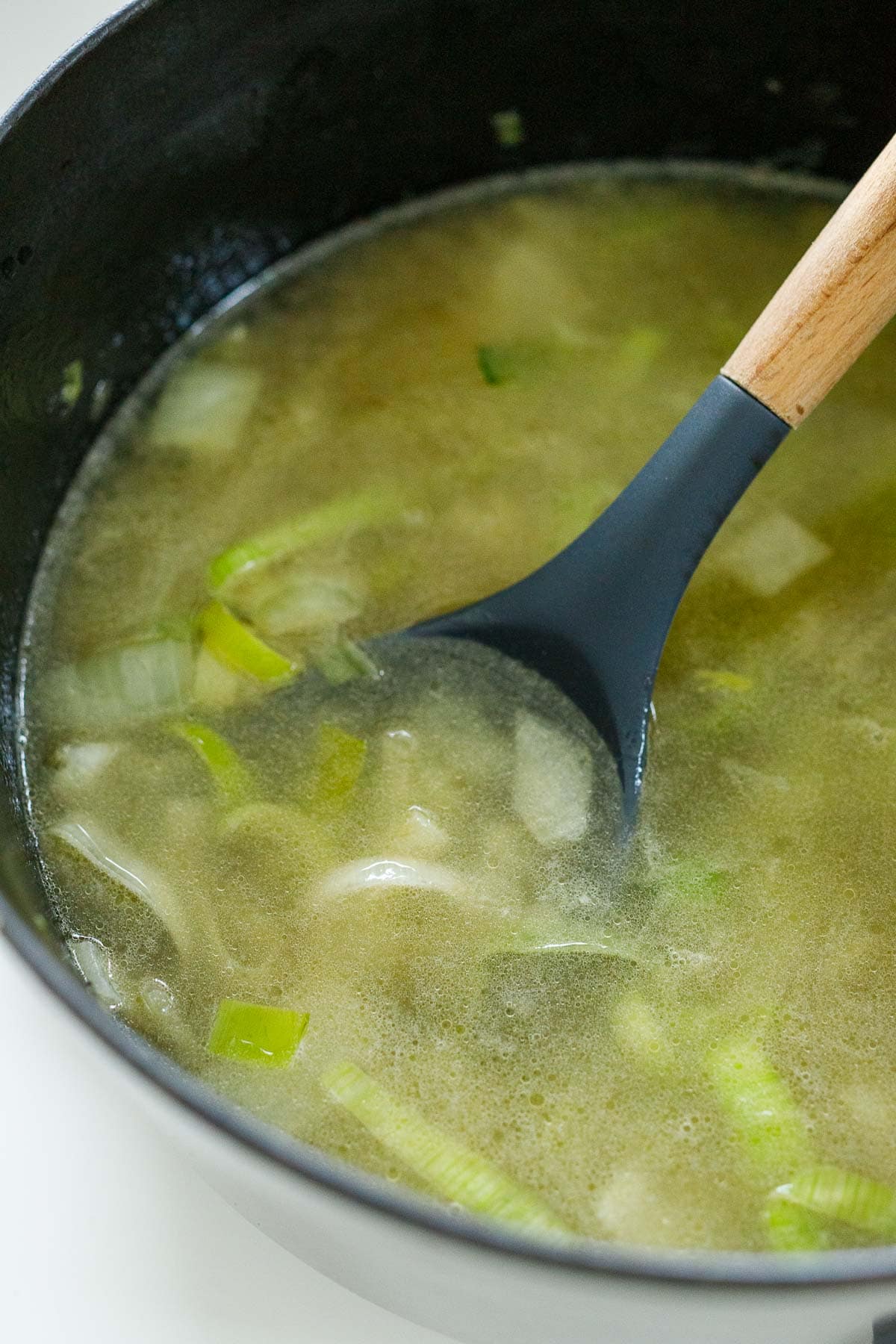 soup with leeks, onion, and water simmering in pot. 