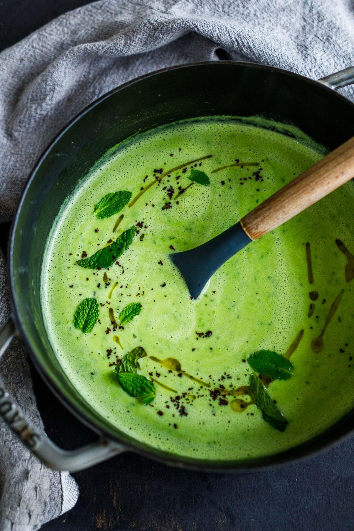 beautiful green minted pea soup with fresh mint, truffle oil, and urfa biber in dutch oven.