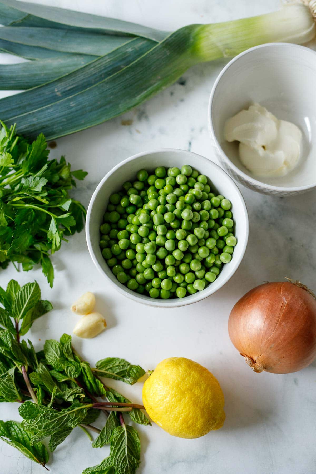 ingredients for minted pea soup - peas, onion, lemon, garlic, mint, parsley, sour cream, leek.