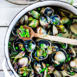 Steamed Clams in a flavorful French-style ,Tarragon White Wine Broth with fresh peas, served with crusty bread to mop up all the flavorful juices!