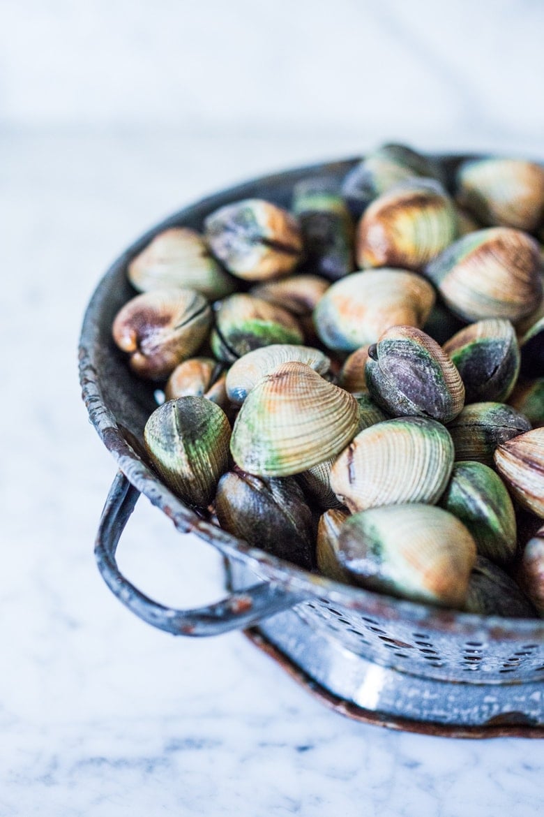 Steamed Clams in a flavorful French-style ,Tarragon White Wine Broth with fresh peas, served with crusty bread to mop up all the flavorful juices! 