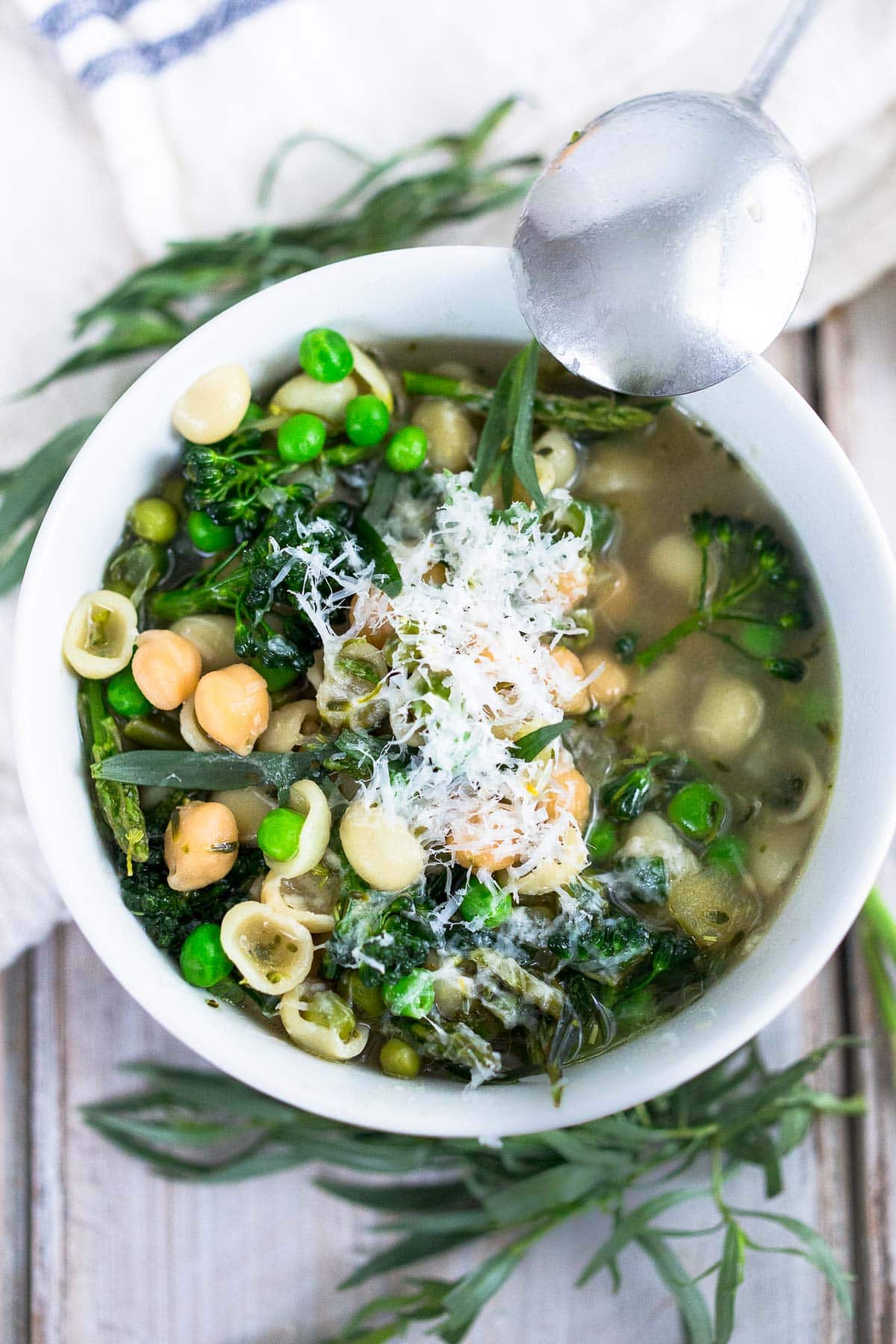spring minestrone soup with chickpeas and orecchiette, fresh spring greens, and grated romano cheese.