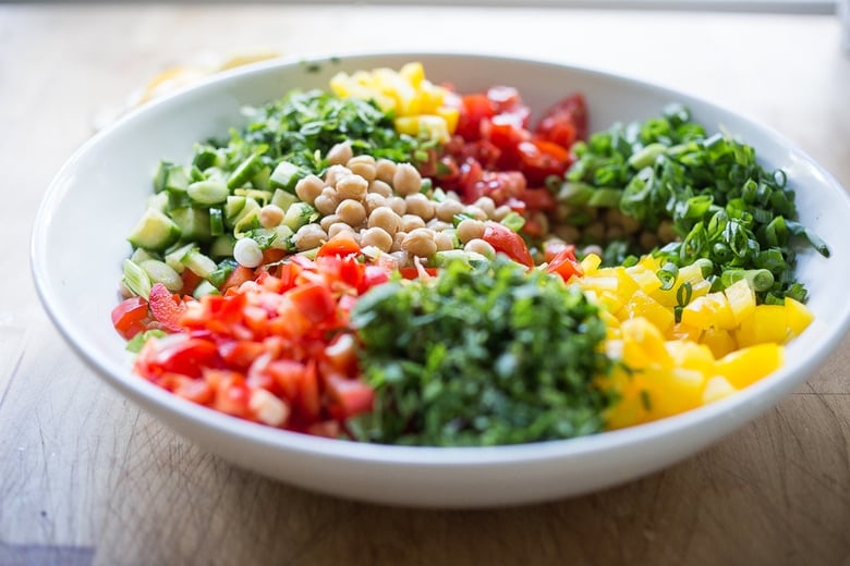 A simple & delicious recipe for Balela Salad, made w/ finely chopped vegetables, chickpeas, fresh herbs, lemon & olive oil. Serve in a pita with tahini sauce or over greens. | www.feastingathome.com