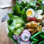 Nordic Nicoise Salad with smoked salmon on a bed of greens with radish, cucumber baby potatoes, capers, dill, and horseradish-spiked nicoise dressing. #nicoise #salad #smokedsalmon #healthylunch #healhtylunches #smokedtrout www.feastingathome.com
