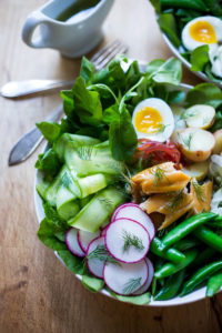 Nordic Nicoise Salad with smoked salmon on a bed of greens with radish, cucumber baby potatoes, capers, dill, and horseradish-spiked nicoise dressing. #nicoise #salad #smokedsalmon #healthylunch #healhtylunches #smokedtrout www.feastingathome.com