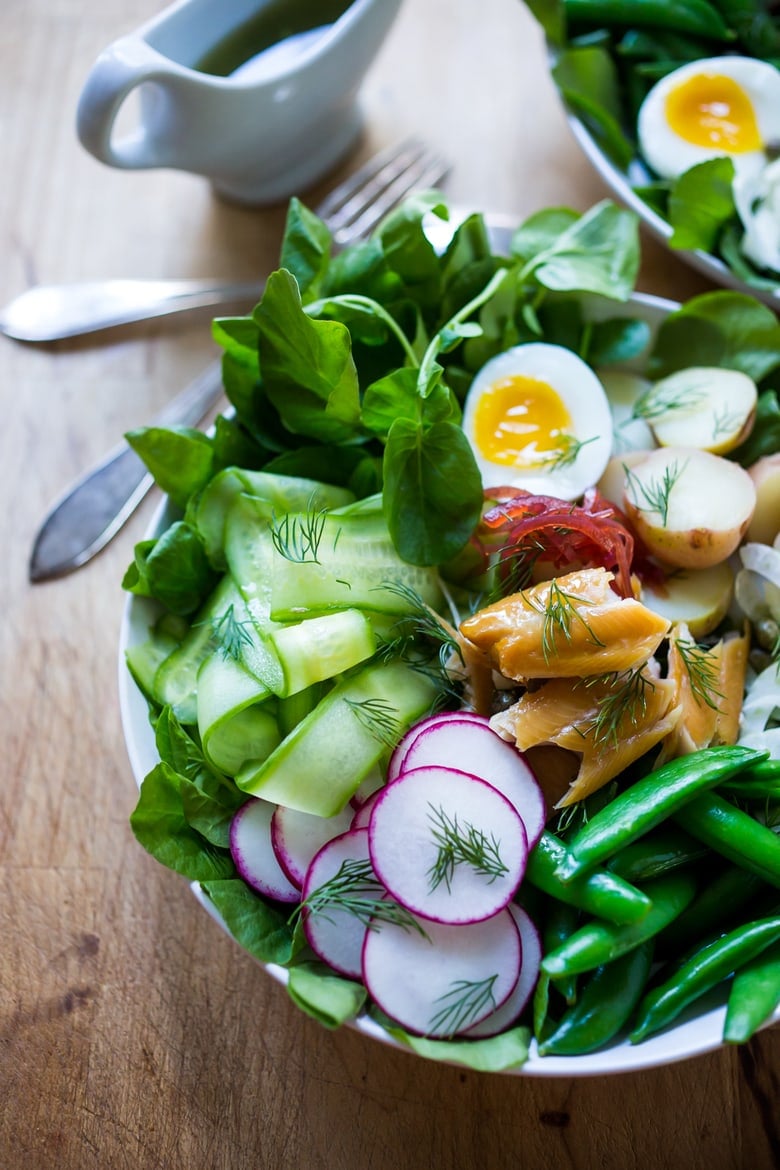 A Scandinavian twist on the classic nicoise salad - Nordic Nicoise Salad is made with smoked fish ( salmon, trout, sardines) or pickled herring, on a bed of watercress, with radish, cucumber ribbons, baby potatoes, capers, dill, chive blossoms and horseradish-spiked nicoise dressing. Fresh and tasty! | www.feastingathome.com