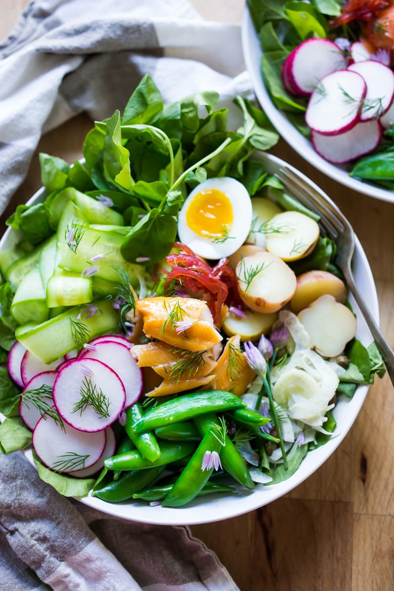 A Scandinavian twist on the classic nicoise salad - Nordic Nicoise Salad is made with smoked fish ( salmon, trout, sardines) or pickled herring, on a bed of watercress, with radish, cucumber ribbons, baby potatoes, capers, dill, chive blossoms and horseradish-spiked nicoise dressing. Fresh and tasty! | www.feastingathome.com