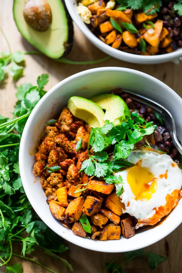 Healthy Yummy Mexican Breakfast Bowls with sweet potatoes, blackbeans, turkey chorizo (optional) avocado, cilantro and an egg. | #breakfastbowls #turkeychorizo #breakfastbowl www.feastingathome.com