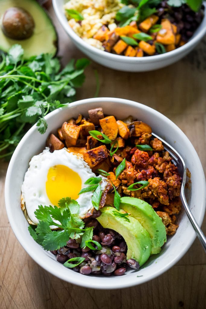 Healthy Yummy Mexican Breakfast Bowls with sweet potatoes, blackbeans, turkey chorizo (optional) avocado, cilantro and an egg. | #breakfastbowls #turkeychorizo #breakfastbowl www.feastingathome.com