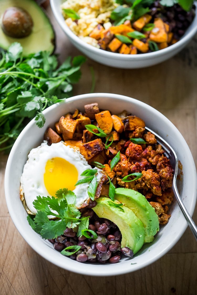 Mexican Breakfast Bowls with sweet potatoes, blackbeans, turkey chorizo (optional) avocado, cilantro and an egg. | #breakfastbowls #turkeychorizo #breakfastbowl www.feastingathome.com