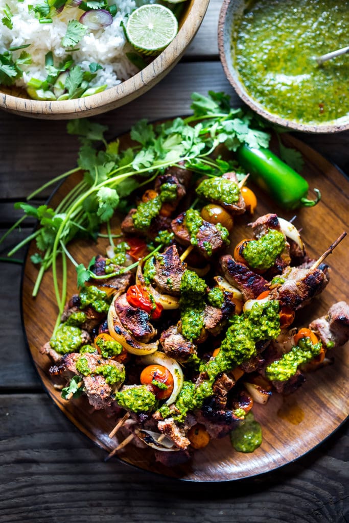 grilled chilean beef kabobs with onions and tomatoes, drizzled with chimichurri sauce.