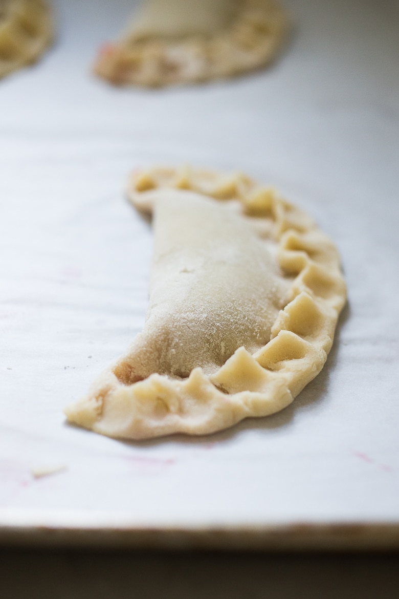 A simple delicious recipe for Strawberry Turnovers or "Hand Pies" , sweetened with maple syrup. Step by step instructions on mastering the "double fold" which prevent the filling from oozing out while baking. | www.feastingathome.com