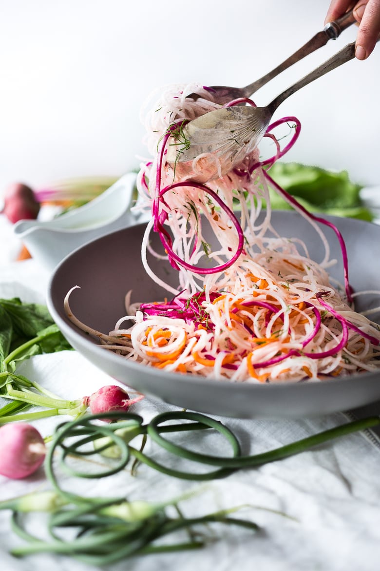 A simple tasty recipe for Tangled Summer Roots- spiralized kohlrabi, beets, turnips, radishes and carrots tossed with a yogurt garlic scape dressing. | www.feastingathome.com