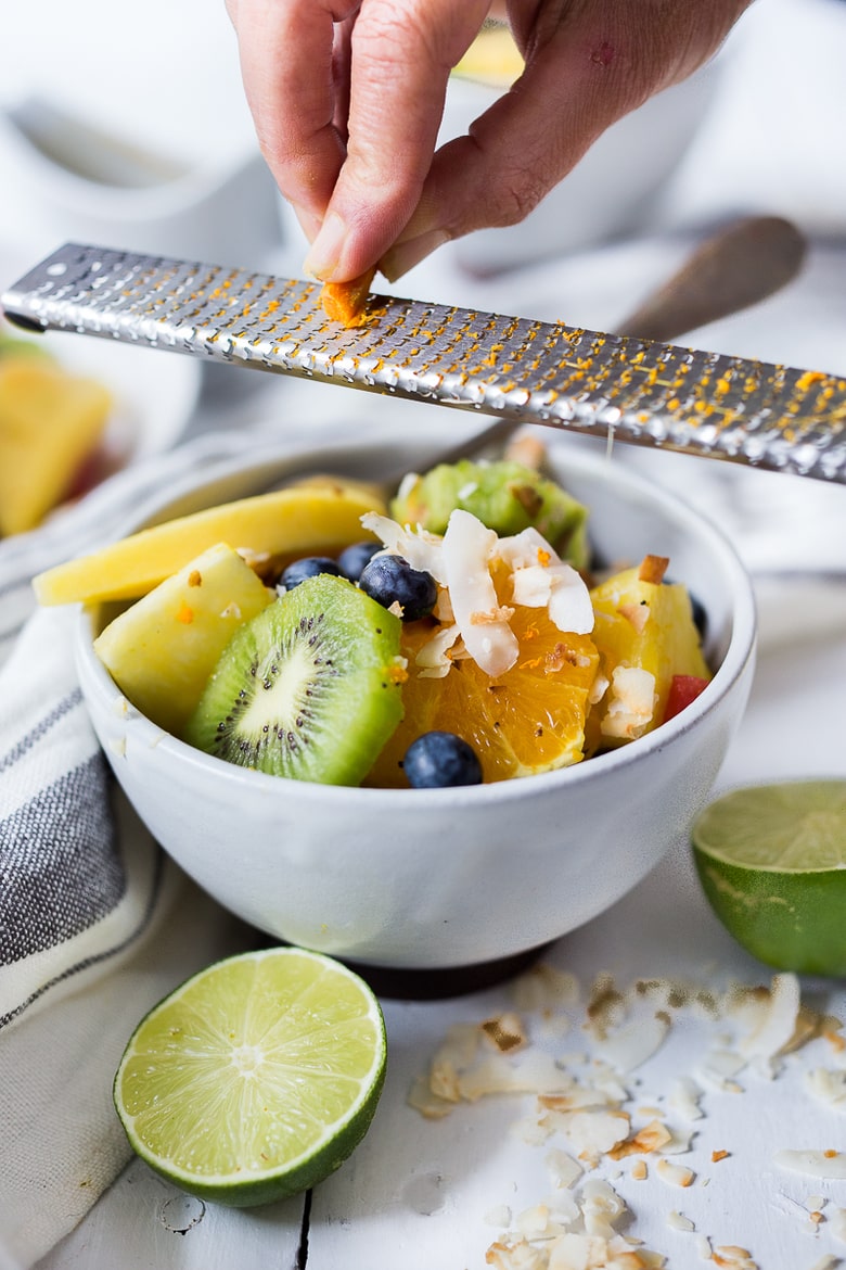 Exotic Turmeric Fruit Salad with fresh grated turmeric root, orange and lime zest and your favorite fruits, topped w/ toasted coconut flakes. Sugar free. | www.feastingathome.com