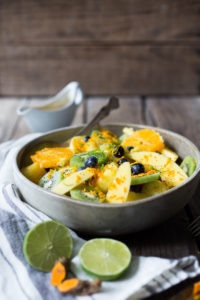 A tropical fruit salad with fresh fruit and berries, seasoned with fresh grated turmeric root, citrus juice and toasted coconut.