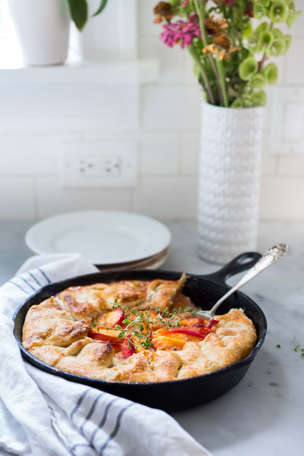Peach pie baked in a skillet on a white counter.