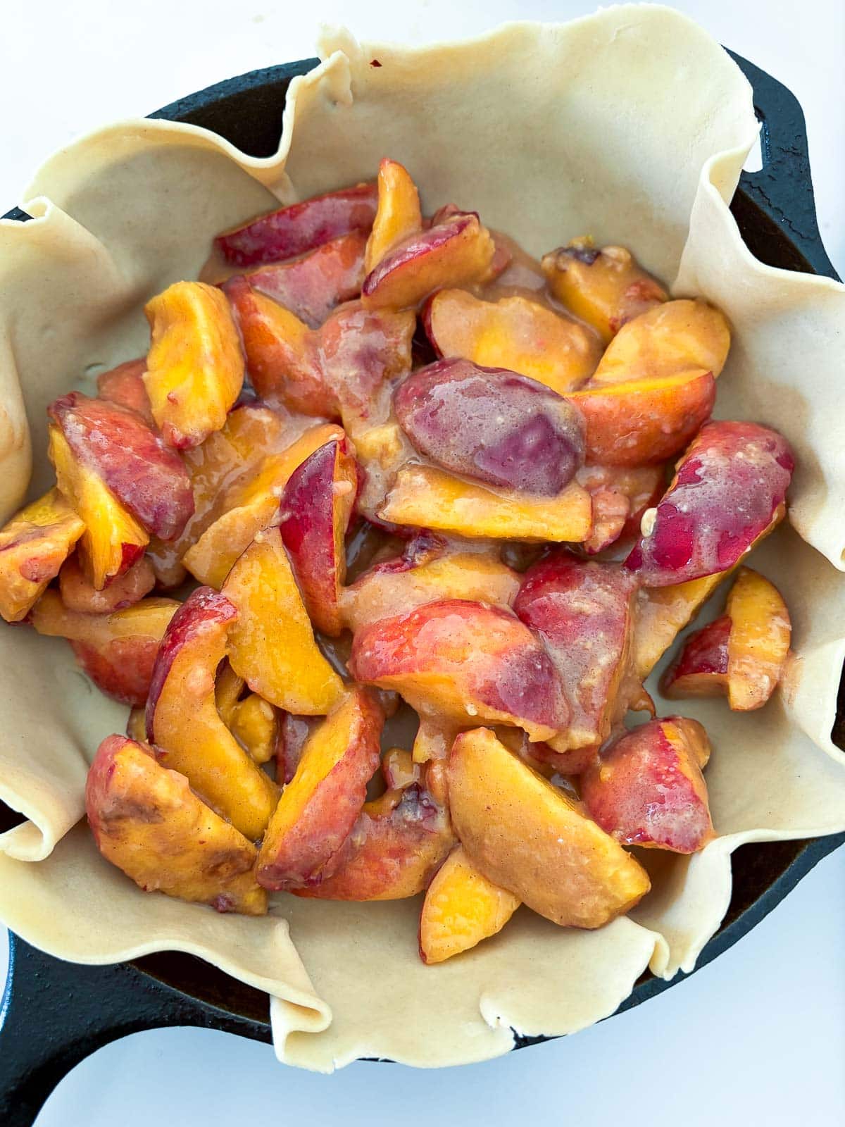 peach filling and pie dough in a cast iron skillet