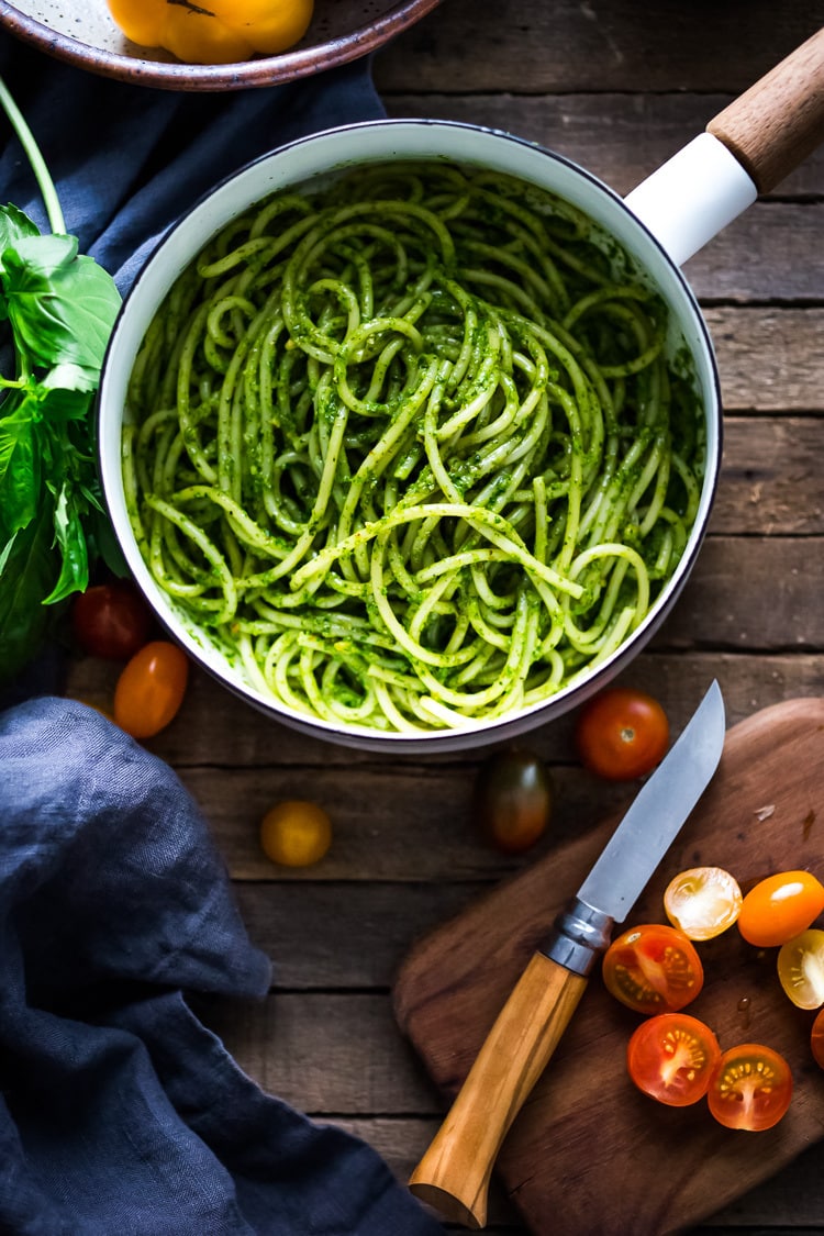 Bucatini Pasta with Arugula Pesto and Heirloom Tomatoes. A fast and flavorful weeknight dinner recipe. This Healthy pasta is Vegan! #bucatini #bucatinipasta #pastawithpesto #arugulapesto www.feastingathome.com 