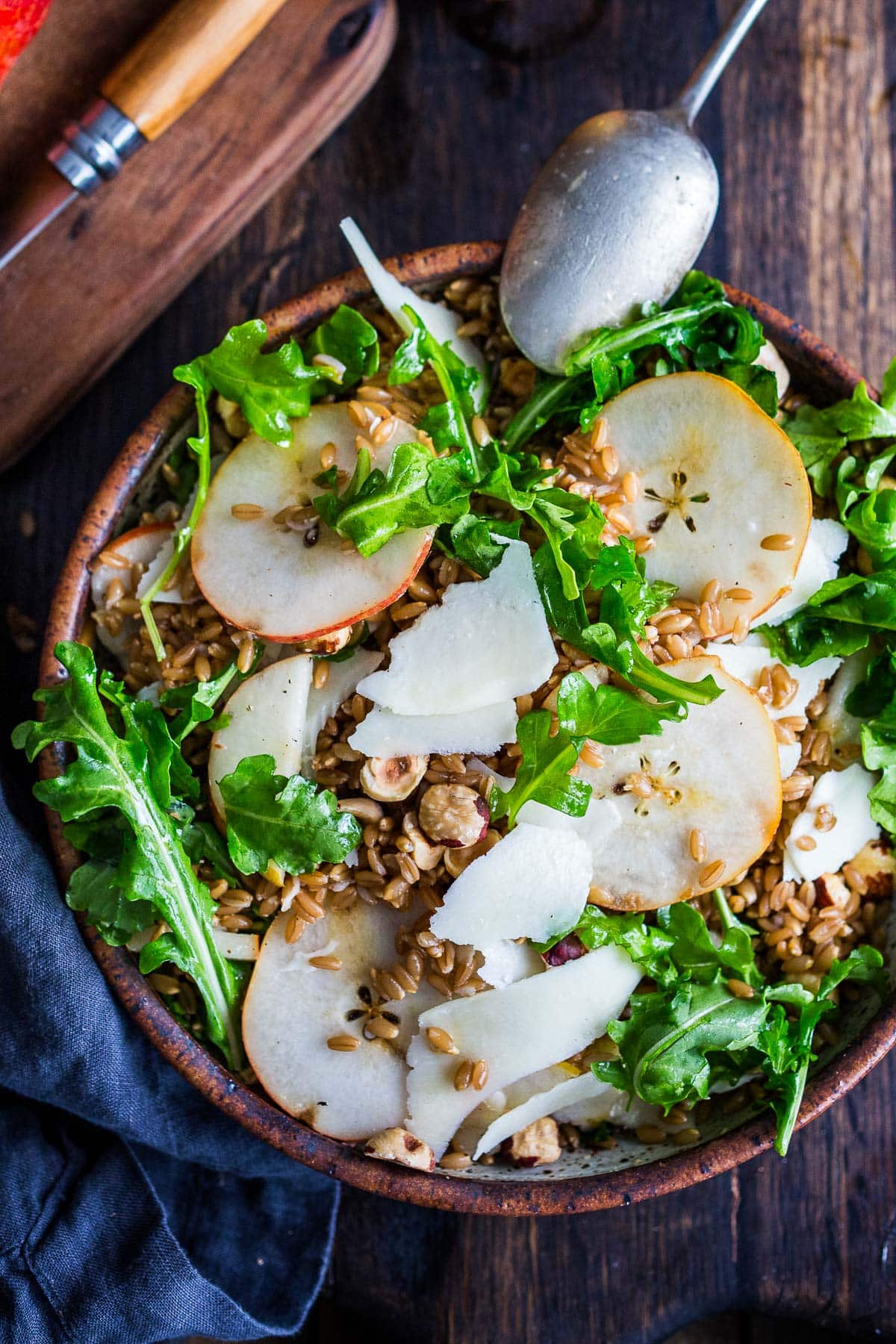bowl of farro salad with sliced pear, shaved pecorino, toasted hazelnuts, and arugula. 