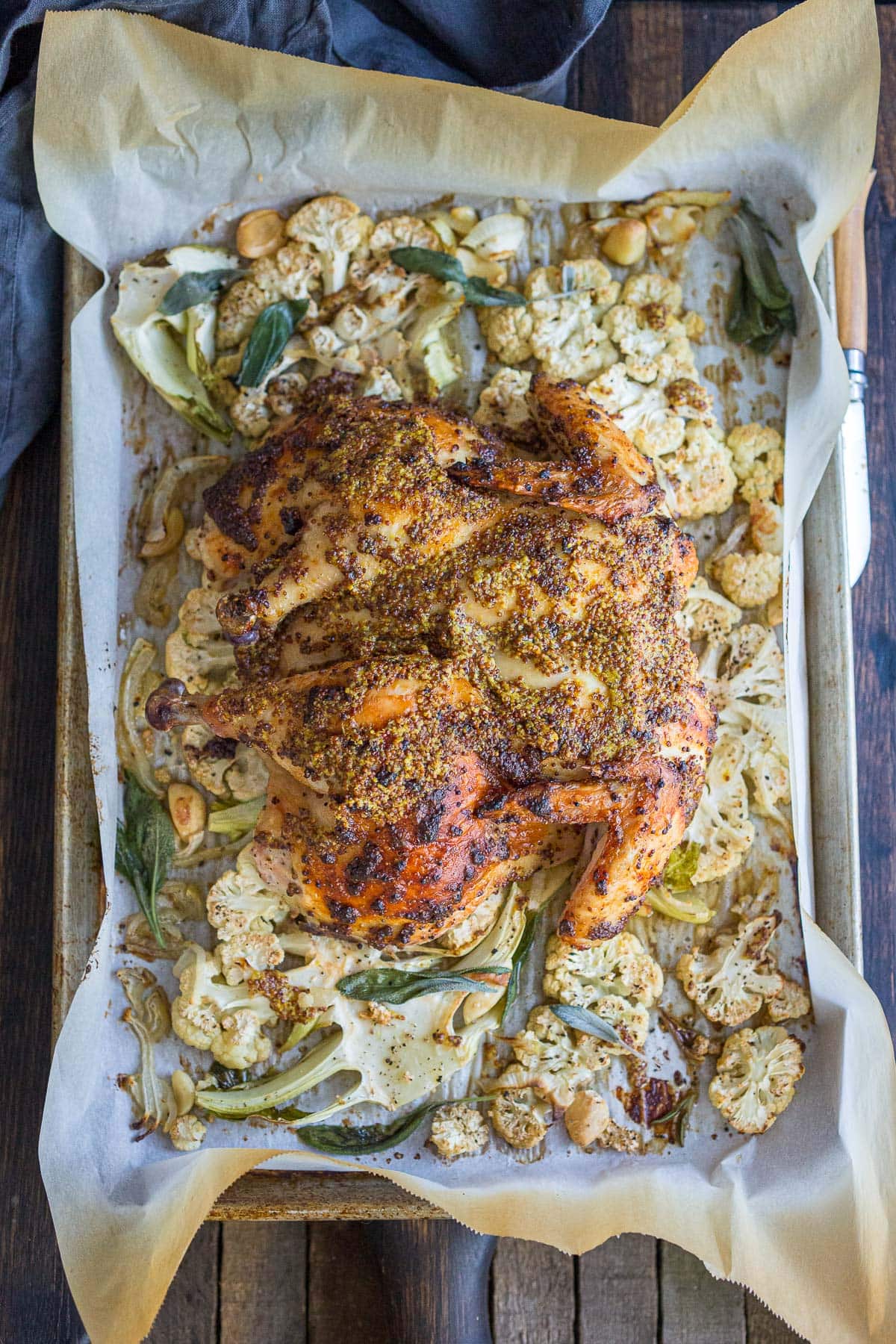 How to spatchcock a chicken: a step by step guide with a video. The chicken is lathered in a mustard seed marinade and roasted over cauliflower steaks- while the drippings from the chicken infuse the cauliflower with goodness and flavor! A delicious one-pan meal