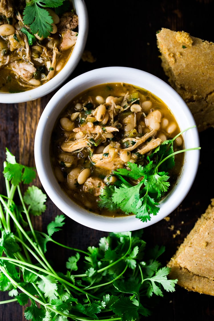 White Chicken Chili is made with with white beans, poblano chilies, cilantro, coriander and lime. Tangy, spicy, this one-pot meal is hearty and delicious! | www.feastingathome.com #whitechili #whitechickenchili #chili #chiliverde 