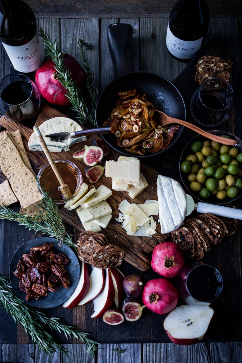 How to make a Holiday Cheese Board! This one is made with Honey Roasted Quince ( or pears), persimmons, figs, maple glazed pecans, olives and gourmet crackers -and an easy step by step guide on how to create a beautiful holiday cheese board! Vegetarian!  | www.feastingathome.com #cheeseboard #thanksgivingappetier #cheeseplatter #cheeseplate