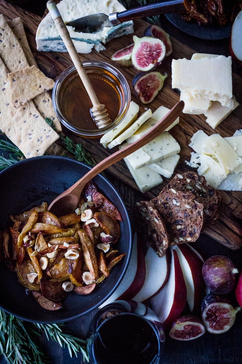 How to make a Holiday Cheese Board! This one is made with Honey Roasted Quince ( or pears), persimmons, figs, maple glazed pecans, olives and gourmet crackers -and an easy step by step guide on how to create a beautiful holiday cheese board! Vegetarian!  | www.feastingathome.com #cheeseboard #thanksgivingappetier #cheeseplatter #cheeseplate