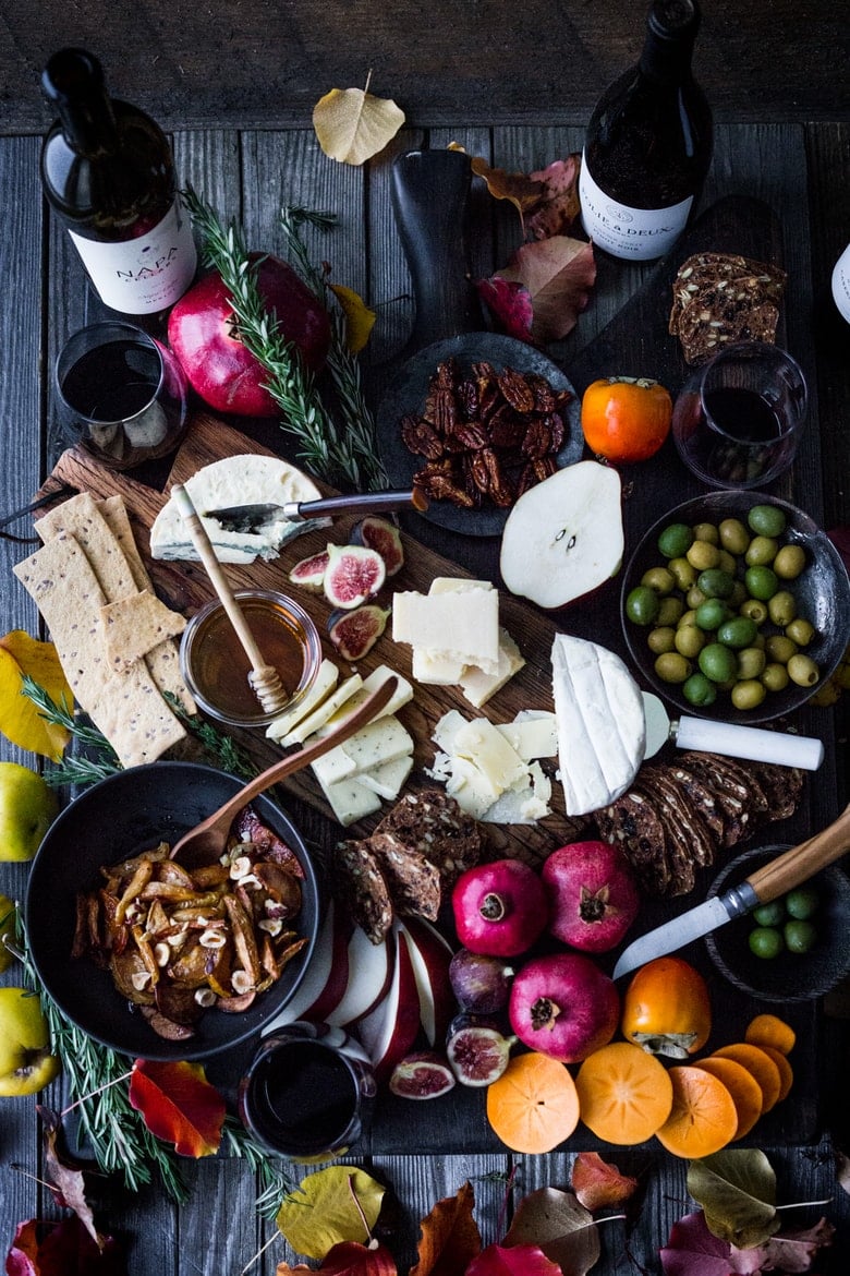 How to make a Holiday Cheese Board! This one is made with Honey Roasted Quince ( or pears), persimmons, figs, maple glazed pecans, olives and gourmet crackers -and an easy step by step guide on how to create a beautiful holiday cheese board! Vegetarian!  | www.feastingathome.com #cheeseboard #thanksgivingappetier #cheeseplatter #cheeseplate