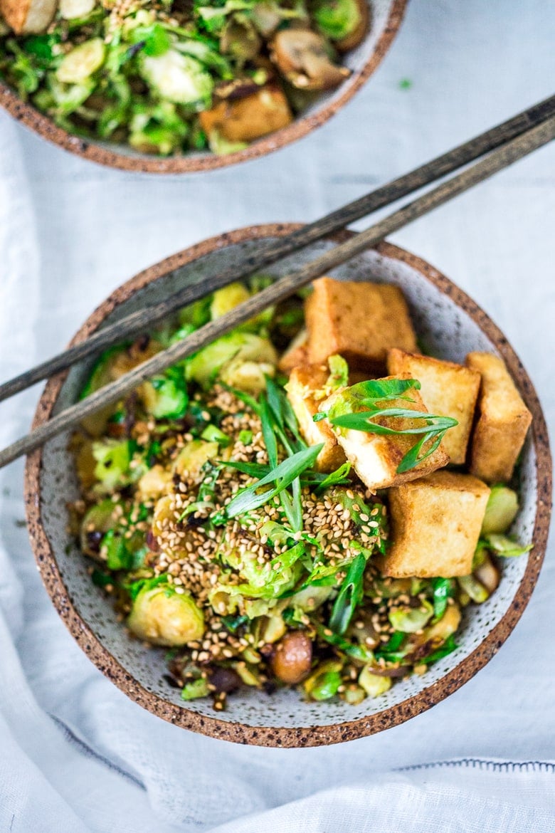 This Stir-fry Tofu, Brussels Sprouts & Mushroom Bowl with scallions and toasted sesame seeds can be made in under 20 minutes and is vegan! Tasty and easy, perfect for a quick healthy weeknight dinner. 