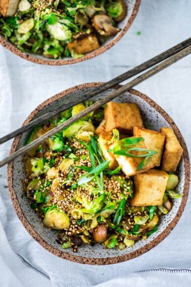 This Stir-fry Tofu, Brussels Sprouts & Mushroom Bowl with scallions and toasted sesame seeds can be made in under 20 minutes and is vegan! Tasty and easy, perfect for a quick healthy weeknight dinner. 