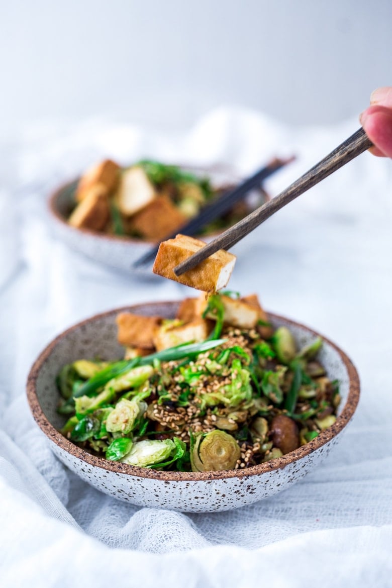 This Stir-fry Tofu, Brussels Sprouts & Mushroom Bowl with scallions and toasted sesame seeds can be made in under 20 minutes and is vegan! Tasty and easy, perfect for a quick healthy weeknight dinner. 