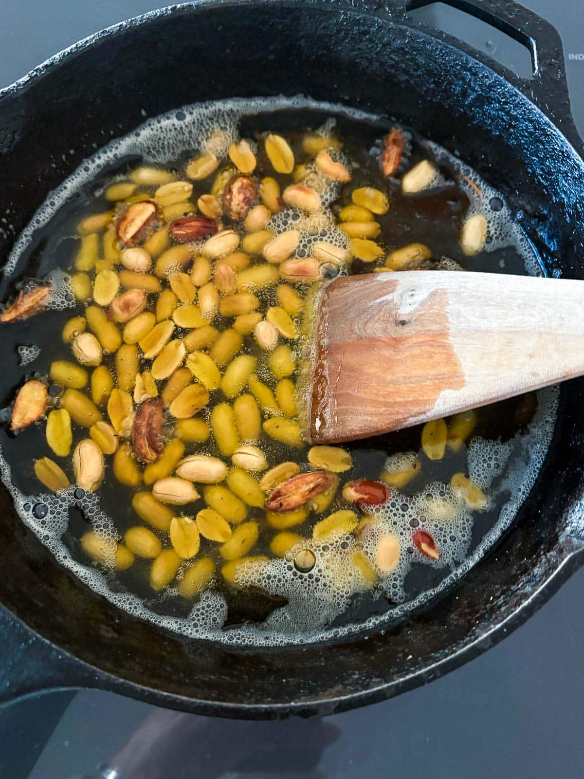 Hot oil in a skillet with garlic and peanuts. 