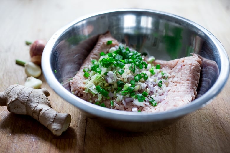 mixing bowl with ground chicken, shallots, ginger, garlic, and green onions.