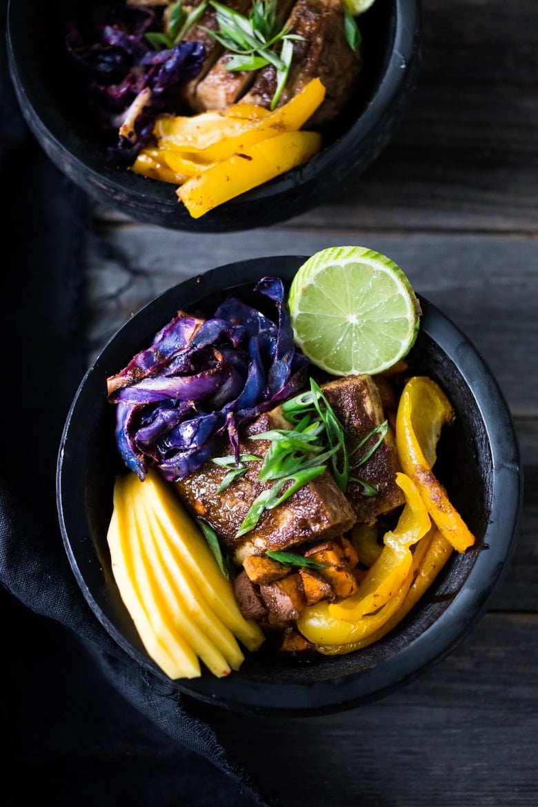 Caribbean-Style Bowl- Roasted cabbage, sweet potatoes and tofu, over a bed of seasoned blackbeans with fresh mango and lime! | #veganbowl #cleaneating #eatclean #vegan #plantbased #buddhabowl #healthybowl #sheetpandinner www.feastingathome.com