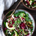 A raw Beet Salad with avocado, power greens, sprouts, toasted pumpkin seeds, pickled shallots, tossed in a flavorful Cashew Basil dressing and drizzled with Cashew Cream for extra richness. A vegan "power salad"! #beetsalad #powersalad #vegansalad #veganbeetsalad #raw #rawbeets