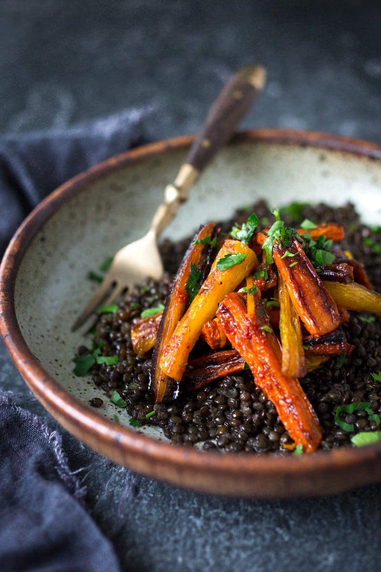 A simple tasty recipe for Roasted Moroccan Carrots- with cumin cinnamon and orange. Serve as a side or over seasoned lentils for a hearty vegetarian meal. | www.feastingathome.com