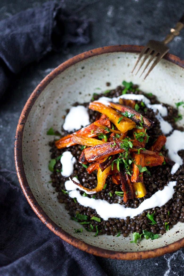 A simple tasty recipe for Roasted Moroccan Carrots- with cumin cinnamon and orange. Serve as a side or over seasoned lentils for a hearty vegetarian meal. | www.feastingathome.com