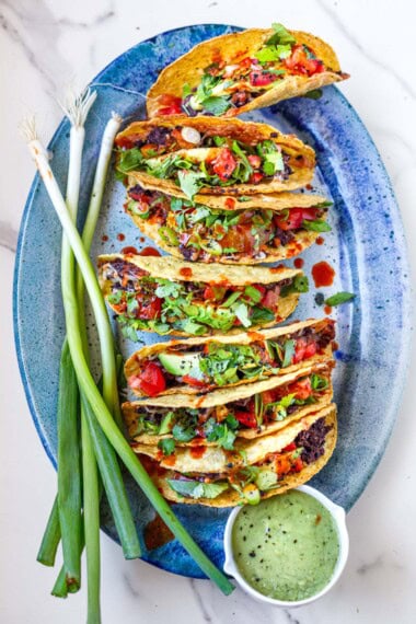 Crispy, oven-baked tacos with refied beans and cheese on a platter.