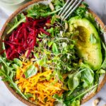 A delicious vegan Raw Beet Salad with Avocado, tender greens, sprouts, toasted pumpkin seeds, pickled shallots, tossed in a flavorful, creamy, vegan Cashew Basil Dressing.
