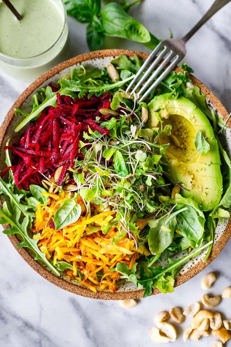 A delicious vegan Raw Beet Salad with Avocado, tender greens, sprouts, toasted pumpkin seeds, pickled shallots, tossed in a flavorful, creamy, vegan Cashew Basil Dressing. 