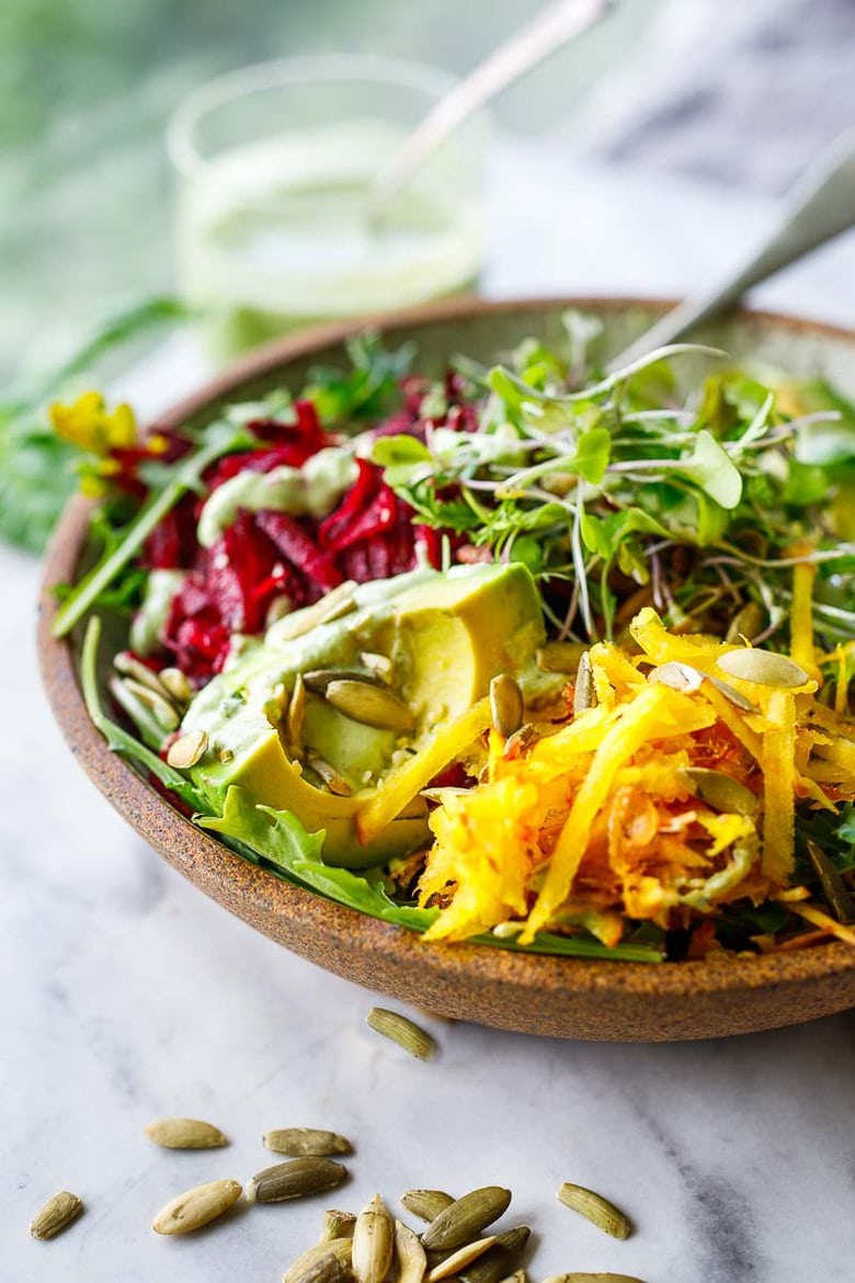 A delicious vegan Raw Beet Salad with Avocado, tender greens, sprouts, toasted pumpkin seeds, pickled shallots, tossed in a flavorful, creamy, vegan Cashew Basil Dressing. 