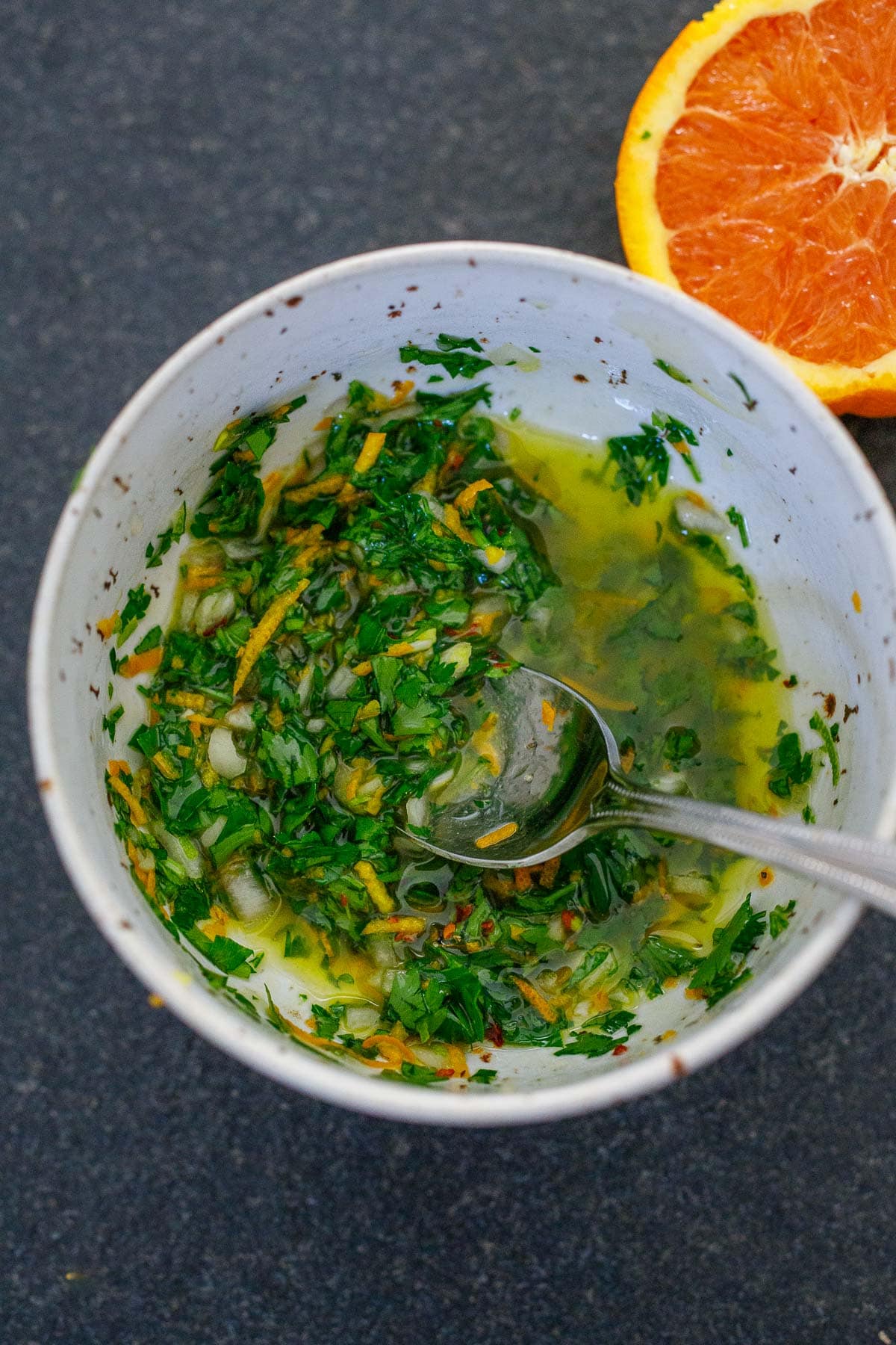 small bowl with herby citrus dressing and spoon.