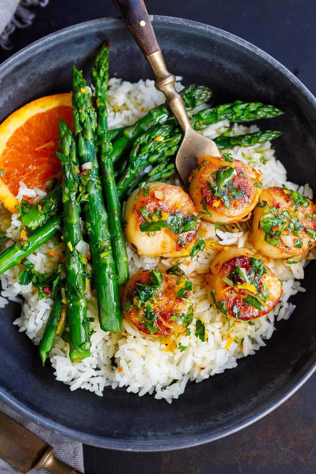 seared scallops with citrus dressing served over rice with asparagus.